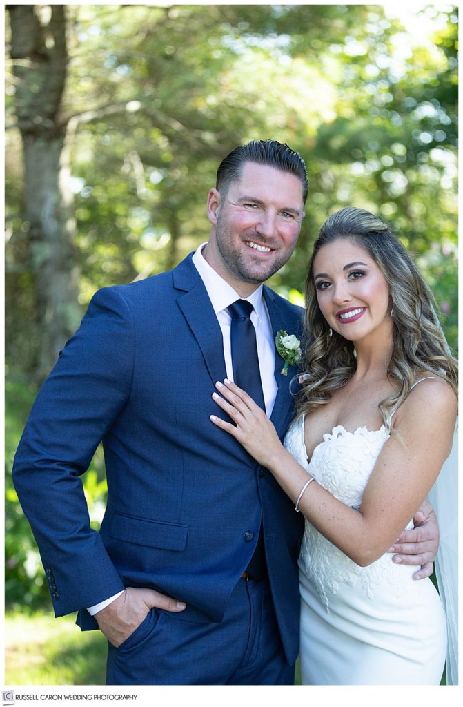 portrait of a bride in white, and a groom in blue, looking at the camera