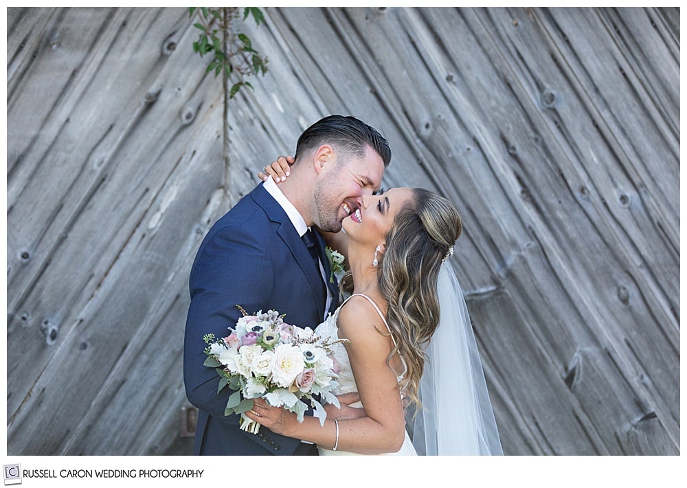 bride and groom facing each other, bride is smiling with her head back, groom is smiling, and about to kiss her