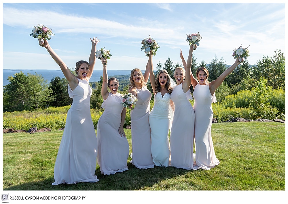 bride in white, whit five bridesmaids in pink, throwing their hands in the air and cheering