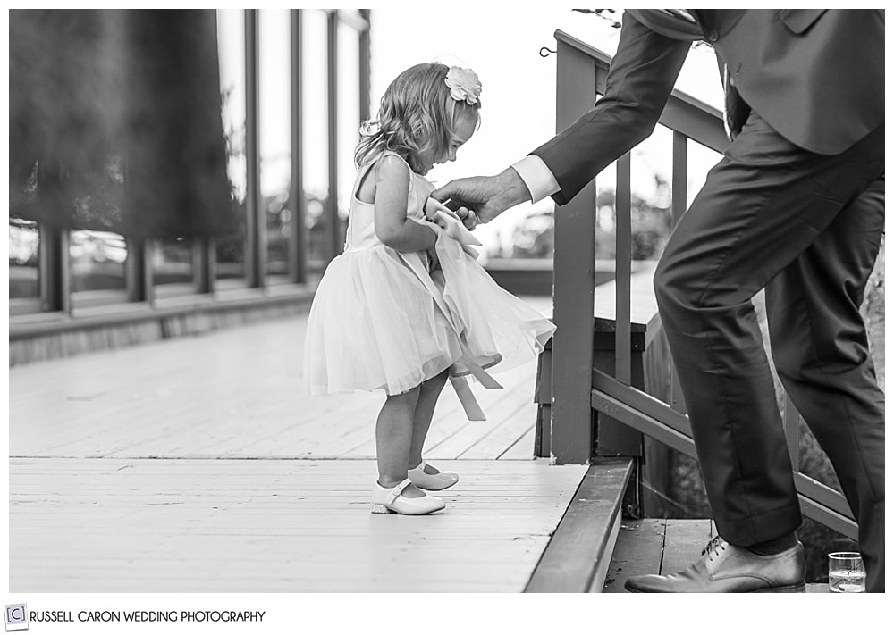 black and white photo of young girl near a stairway, with her father's arm coming in to help