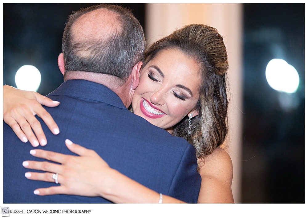 bride dancing with her father, his back is to the camera, the bride has her chin on his shoulder, and is smiling