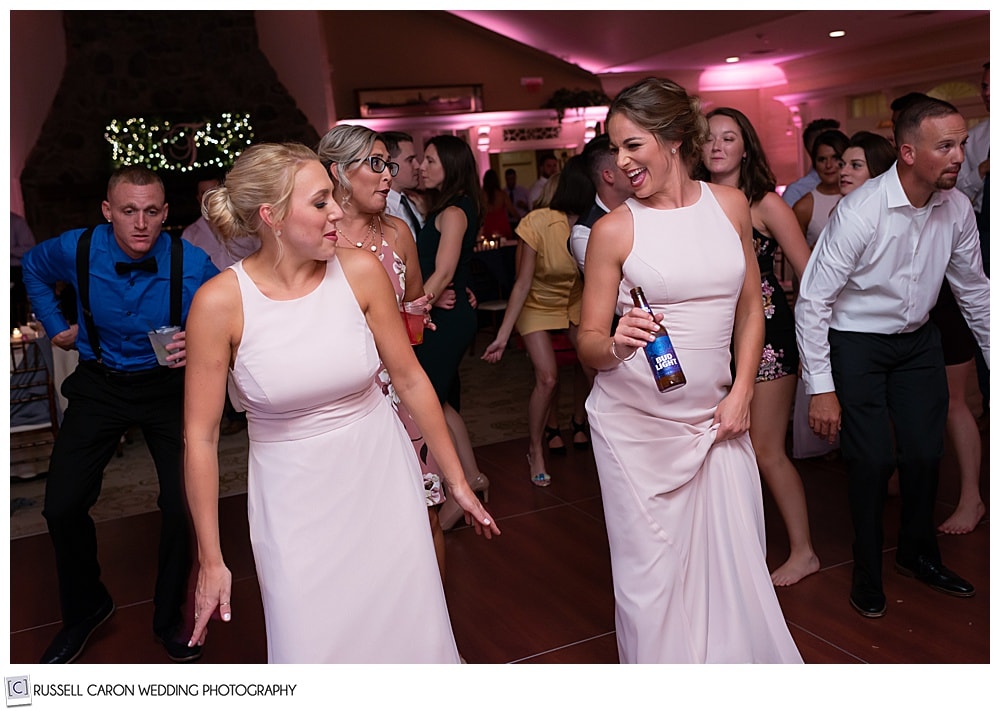 bridesmaids in pink, dancing at an elegant point lookout wedding in Maine