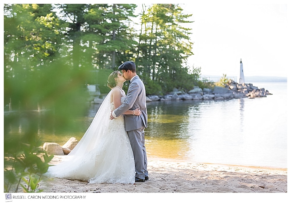 Bride and groom kissing near the lighthouse during their Frye Island wedding, Sebago Lake