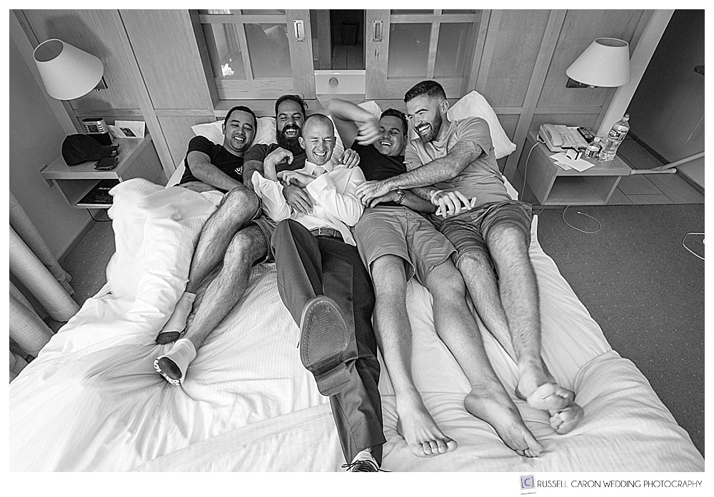 groom and groomsmen horsing around on a bed