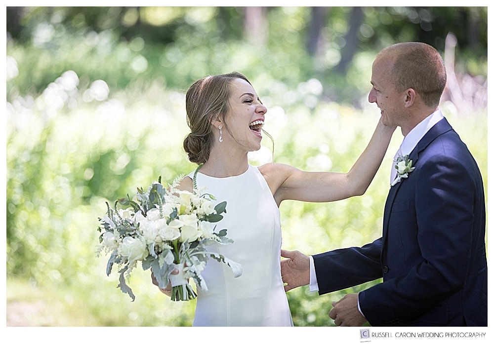 bride laughing and touching groom's face during wedding day first look photo session