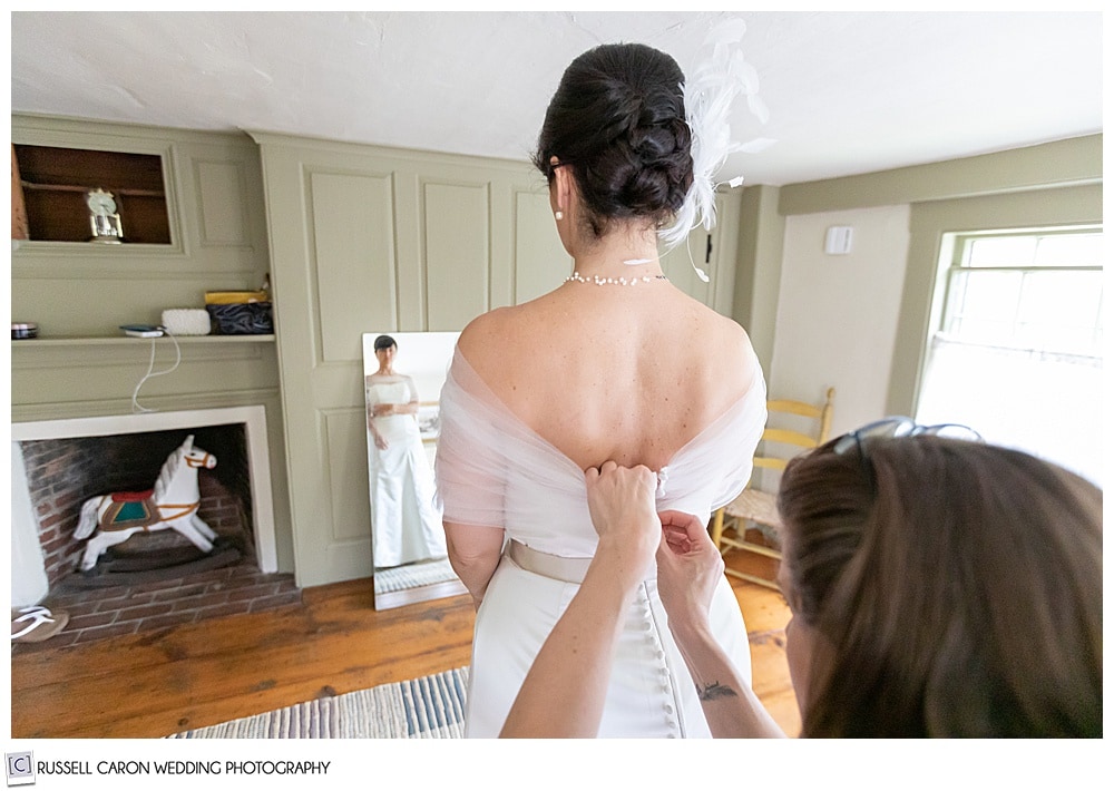 bride getting dressed with full length reflection in mirror