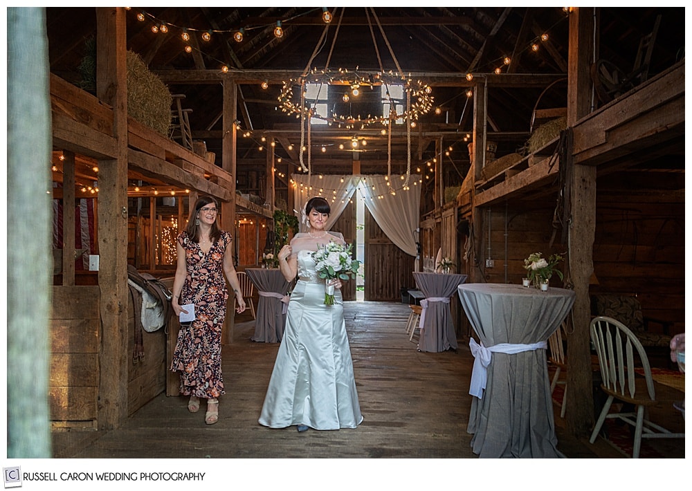 bride and maid of honor walk through wedding barn