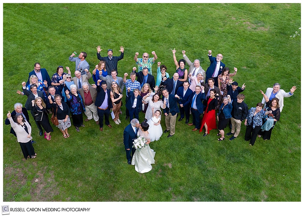 maine drone wedding photo of bride and groom with their friends and family in a field