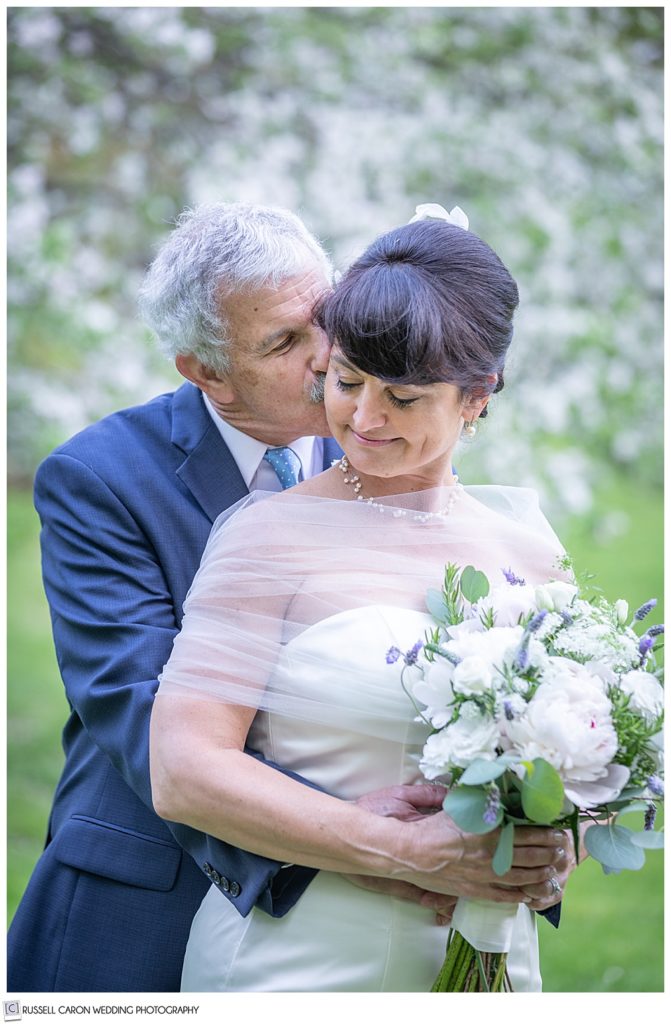 groom standing behind bride kissing her cheek