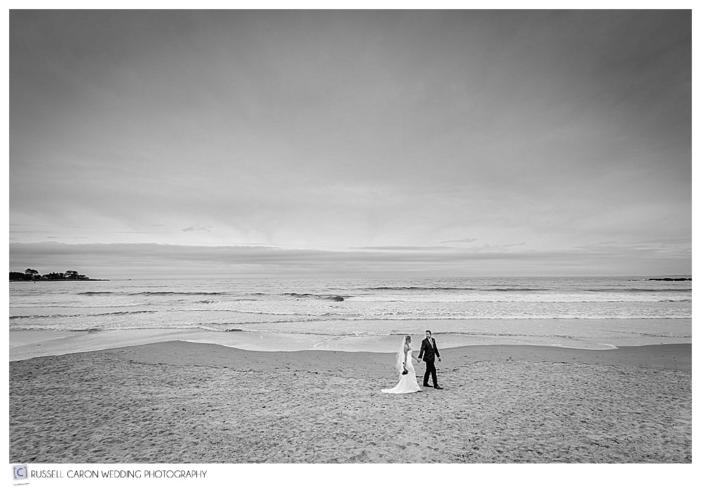 bride and groom walking hand in hand on the beach