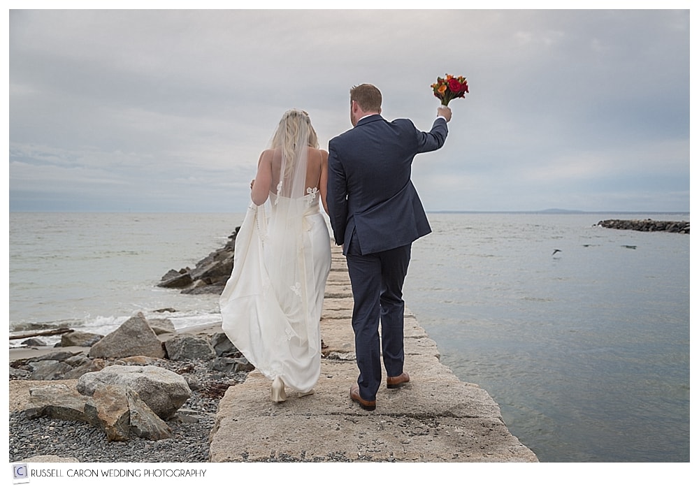 bride and groom walking along breakwater
