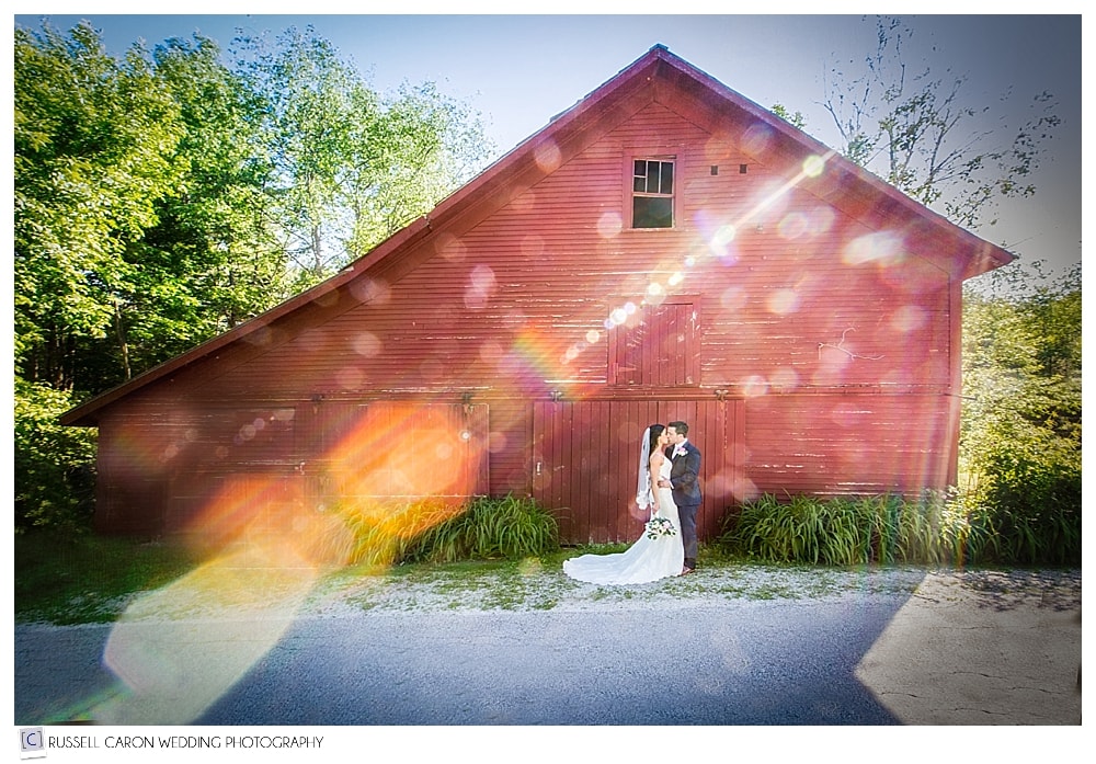 bride-and-groom-kissing-in-front-of-red-barn