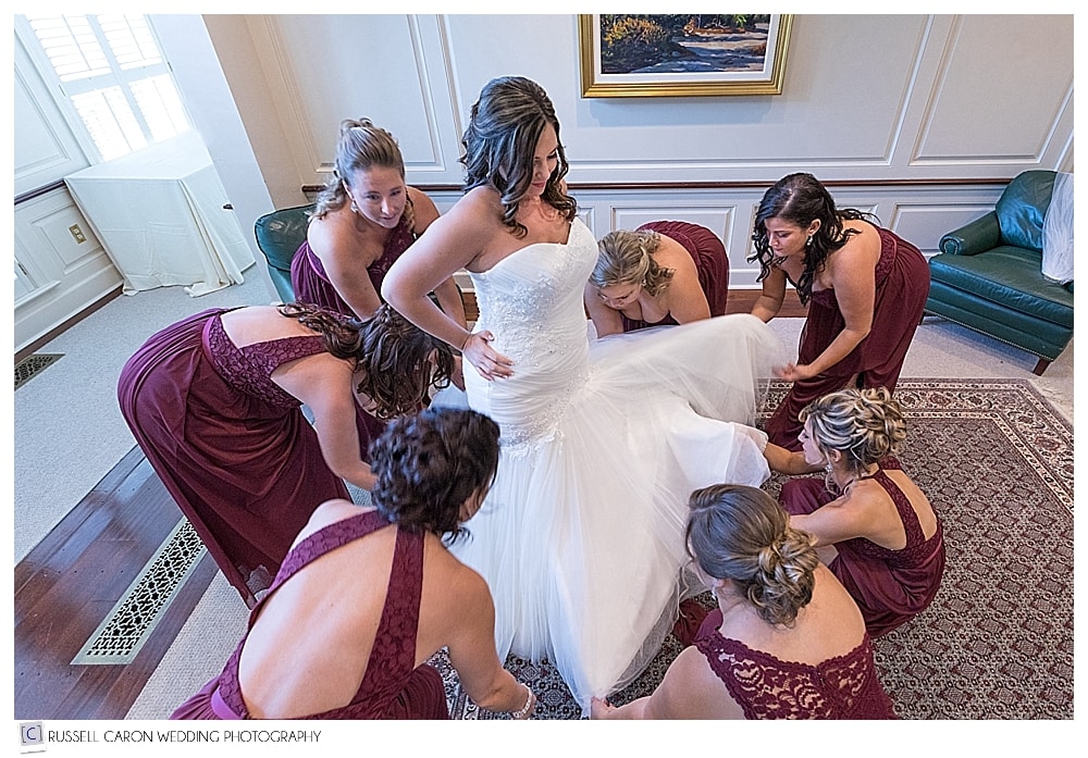 bridesmaids helping bride with wedding dress