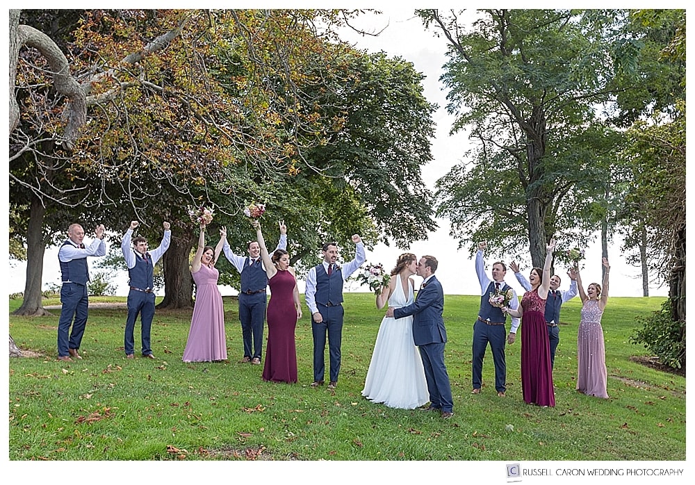 bridal party cheering while bride and groom kiss