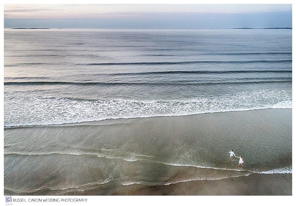 Man and woman walking on Old Orchard Beach, Maine drone wedding photographers