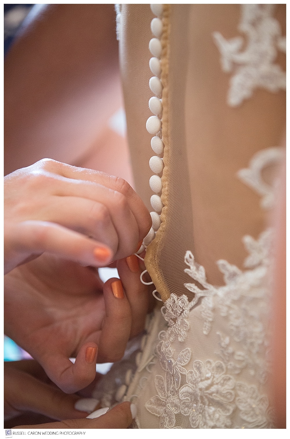 bridesmaid buttoning bride's dress