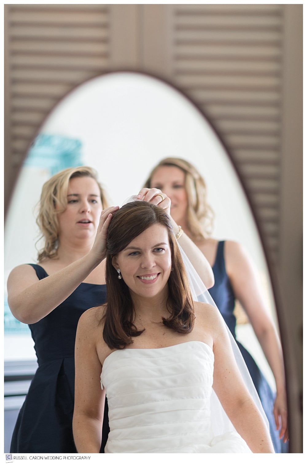 bride with bridesmaids putting in her veil