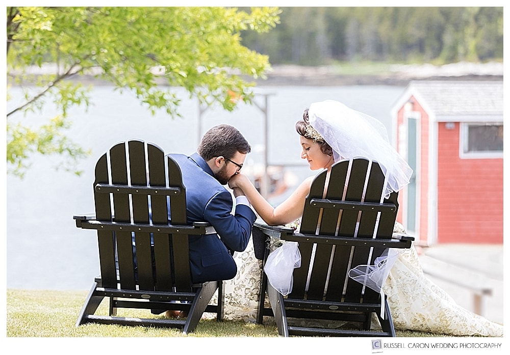 bride and groom sitting in adirondack chairs at their oceanside maine wedding at sebasco harbor resort