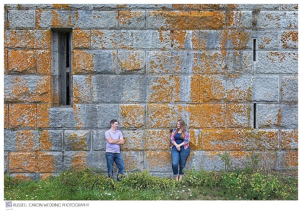 man and woman standing against a wall at Fort Popham during Popham Beach engagement session