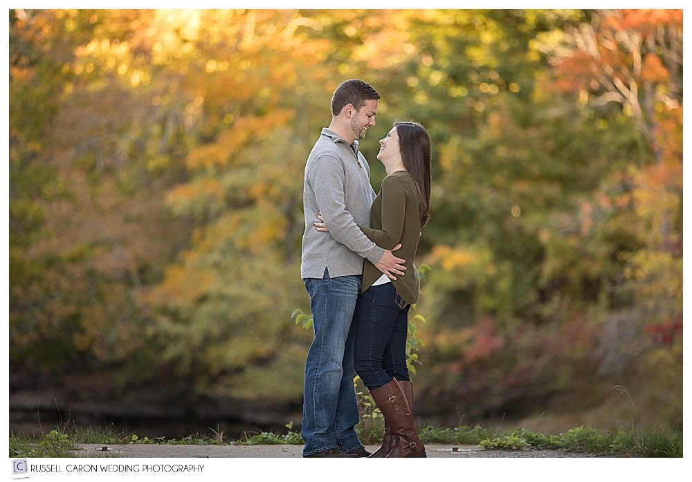 engaged couple standing together in the fall foliage