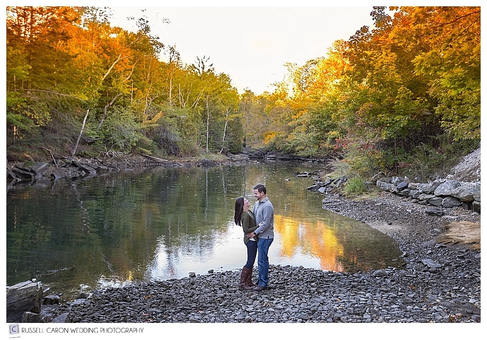 engaged couple standing together amid fall foliage