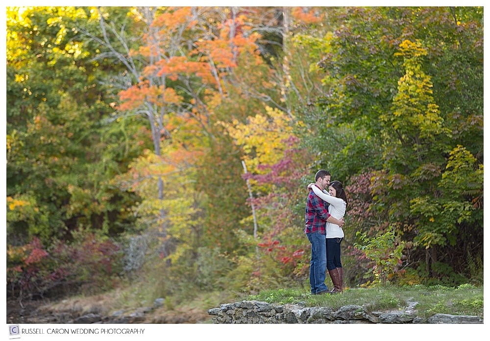 engaged couple standing in the fall foliage
