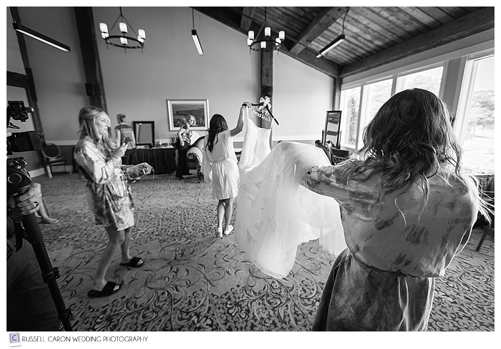 bride and bridesmaid carrying wedding gown