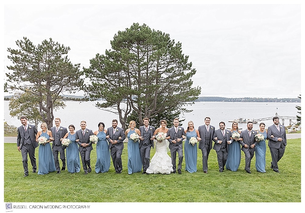 bridal party walking arm in arm on the lawn at the Spruce Point Inn, Boothbay Harbor, Maine