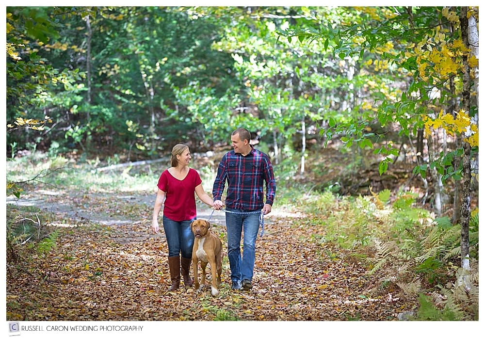 man and woman walking in the leaves with dog