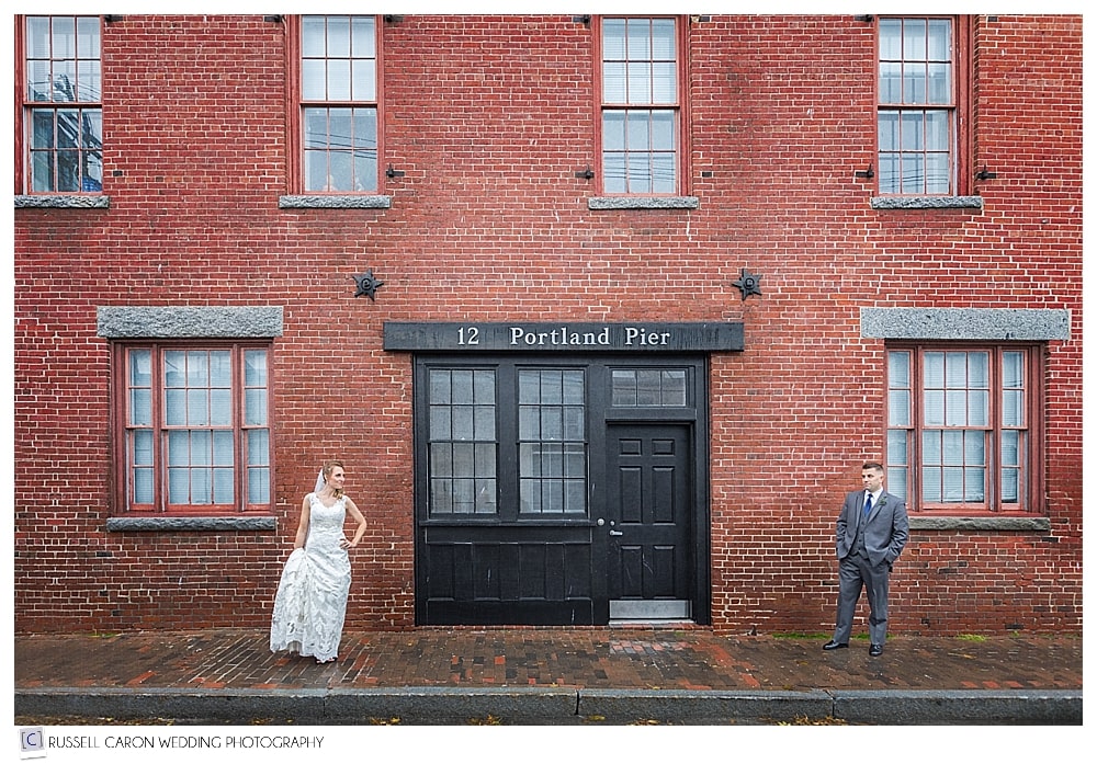 bride and groom in front of a brick wall