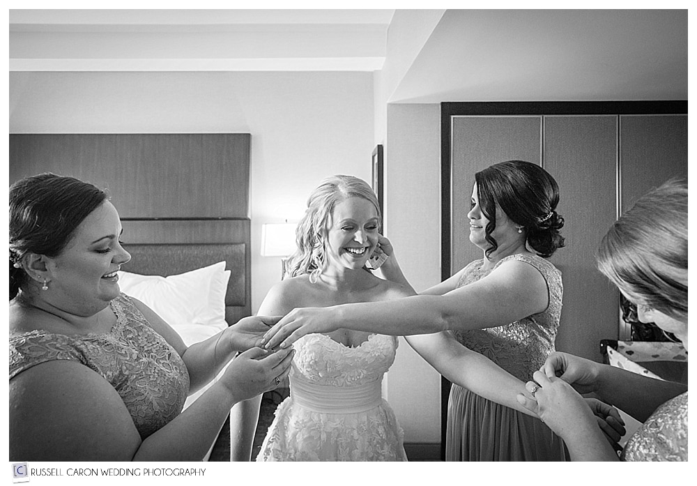 bridesmaids helping bride with jewelry