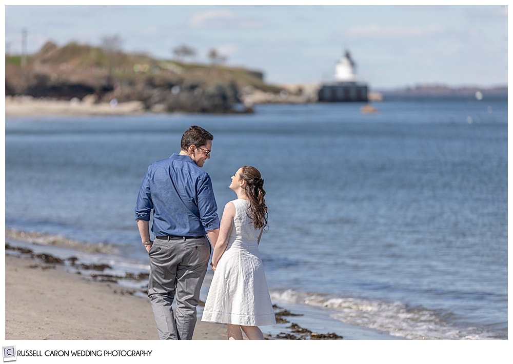 a couple is walking hand in hand near the water at willard beach, south portland, maine