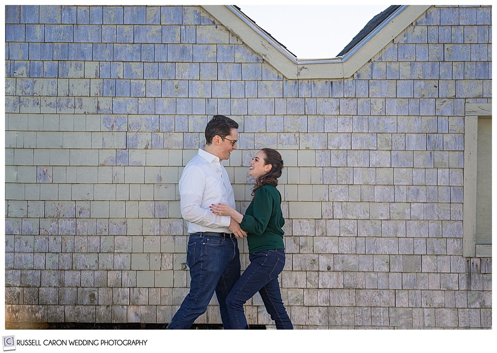 man and woman walking toward each other in front of a shingled building