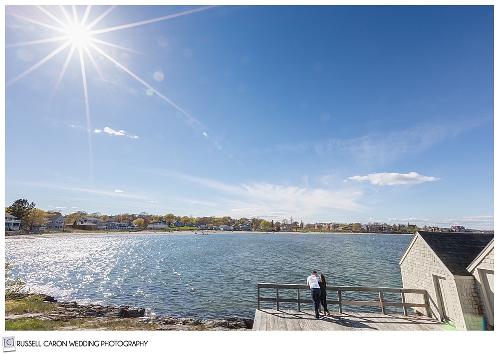 a man and woman leaning against a railing together, looking out over willard beach, south portland, maine