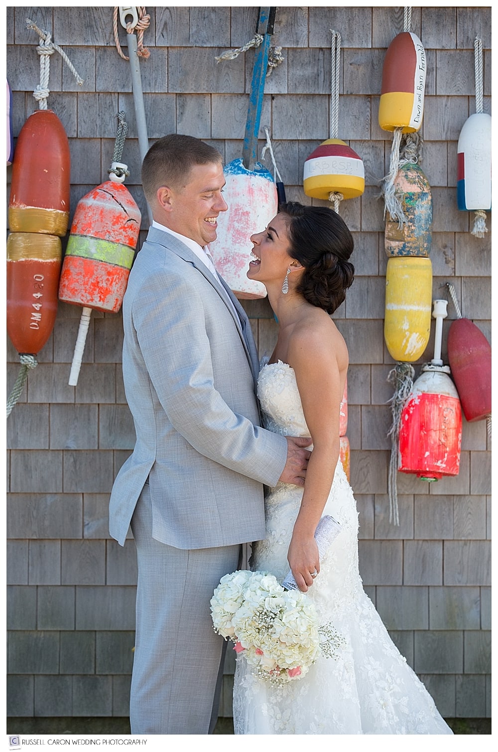 bride and groom in front of lobster buoys