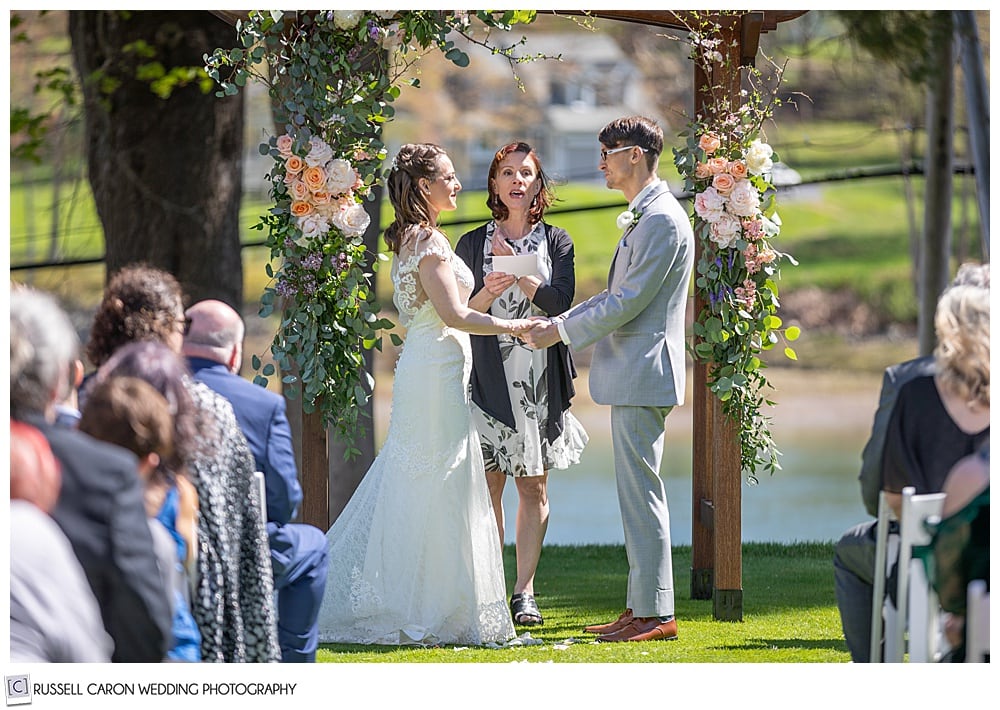 bride and groom standing in front of an officiant, at the outdoor ceremony site at York Golf and Tennis Club