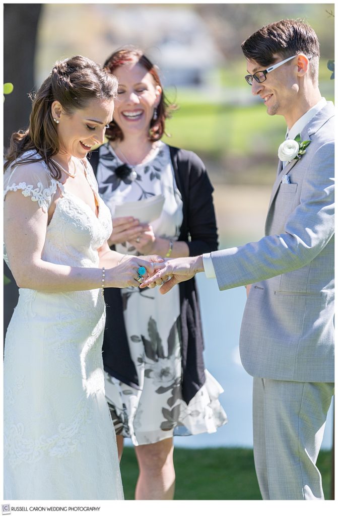 bride putting wedding ring on groom's finger