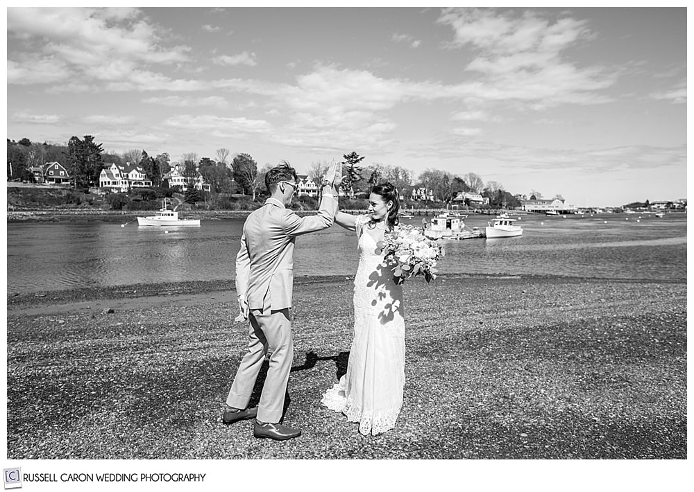 black and white photo of bride and groom giving each other a high five