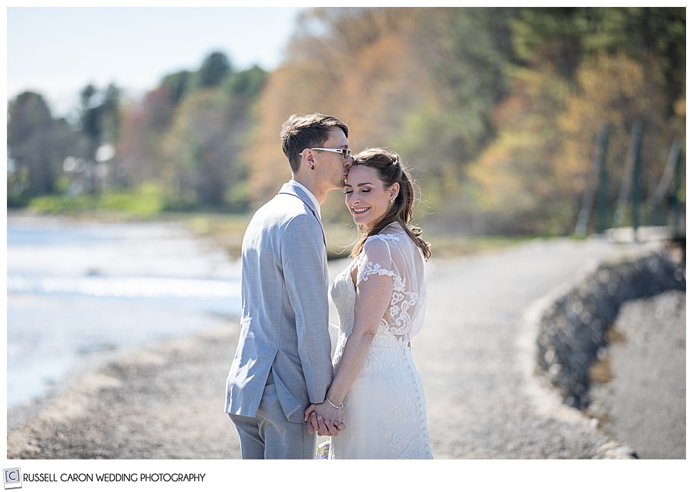 groom kissing his bride on the forehead as she smiles