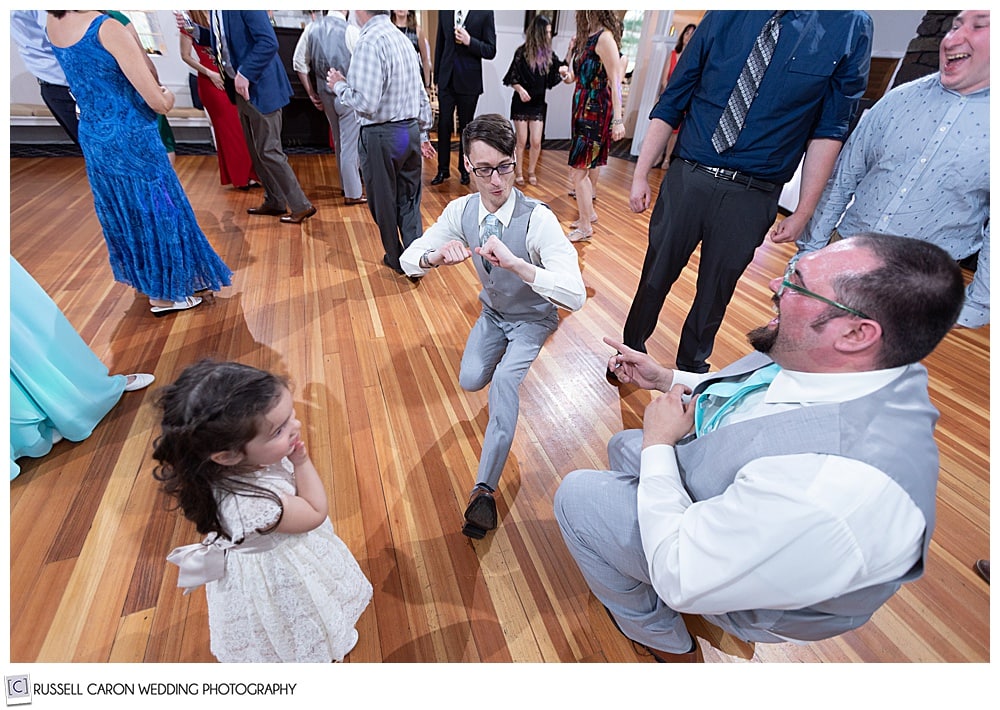 groom dancing with flower girl and groomsman