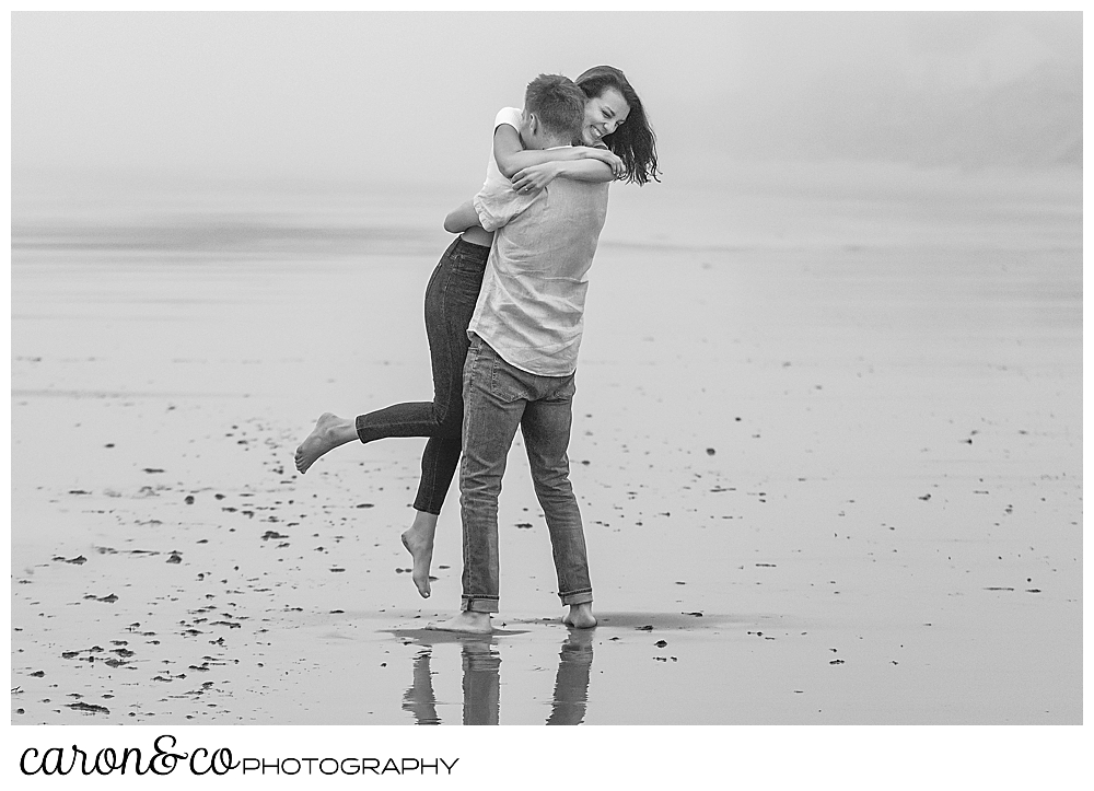 dreamy Maine engagement photo of a man picking up a woman, her arms are around his neck