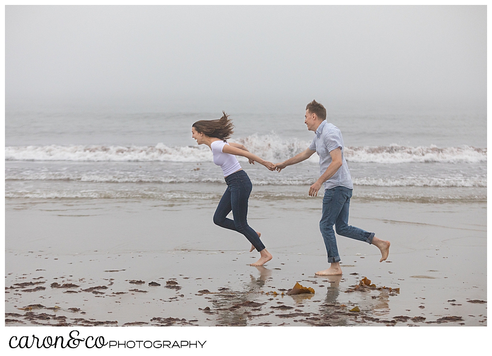 man and woman running along the shore at Biddeford Pool Beach, during a dreamy Maine engagement session