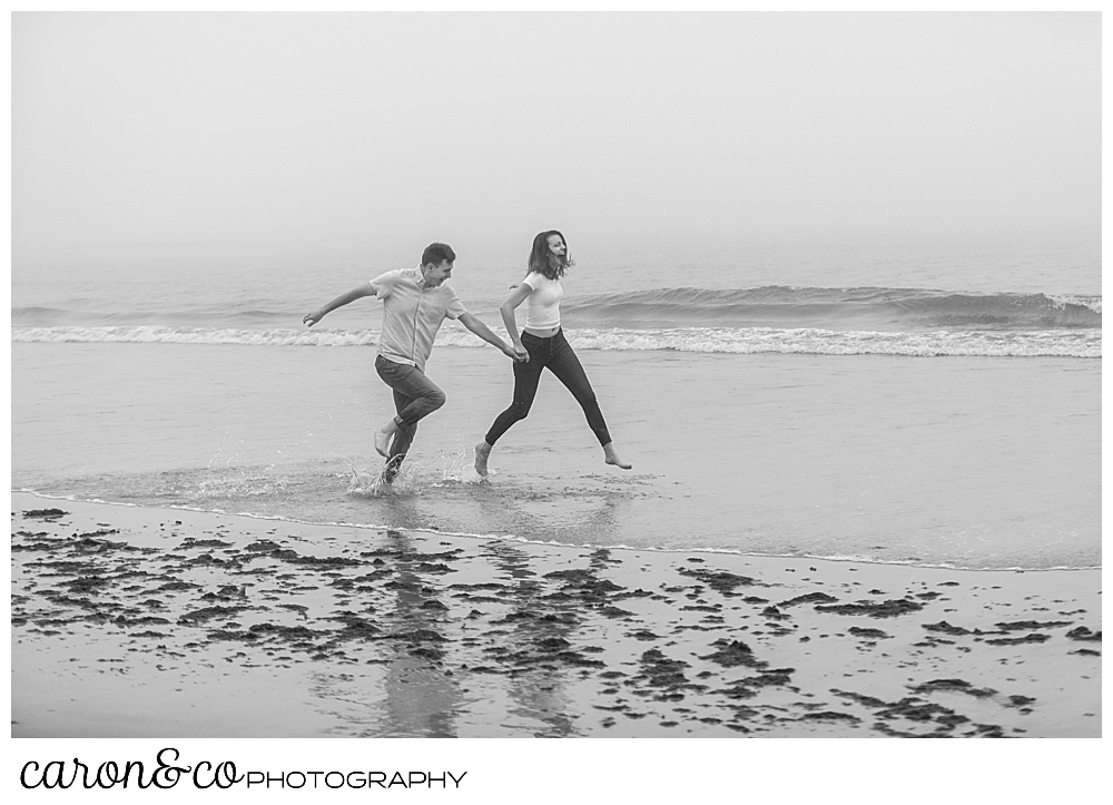 black and white photo of a man and woman running in the surf at Biddeford Pool Beach