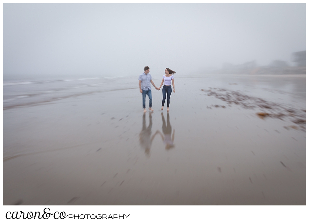 man and woman at Biddeford Pool beach, in the fog, holding hands and walking along the water