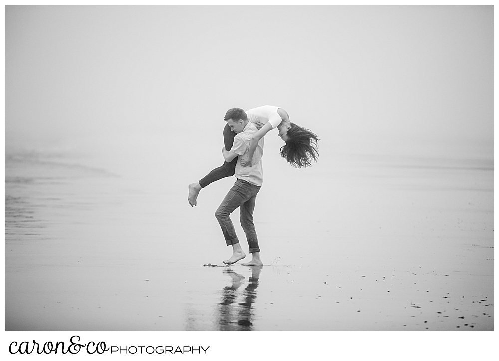 black and white photo of a man carrying a woman over his shoulder during a dreamy Maine engagement photo session