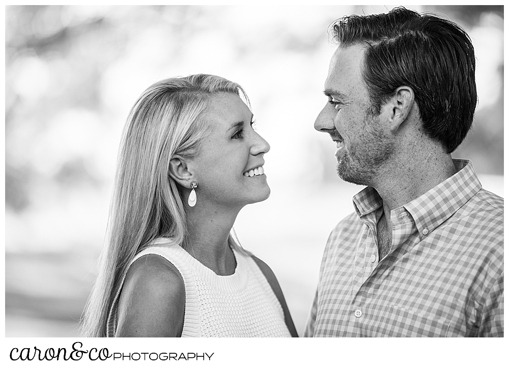 black and white photo of a man and woman standing face to face, smiling during their Boothbay Harbor engagement, Boothbay harbor, Maine