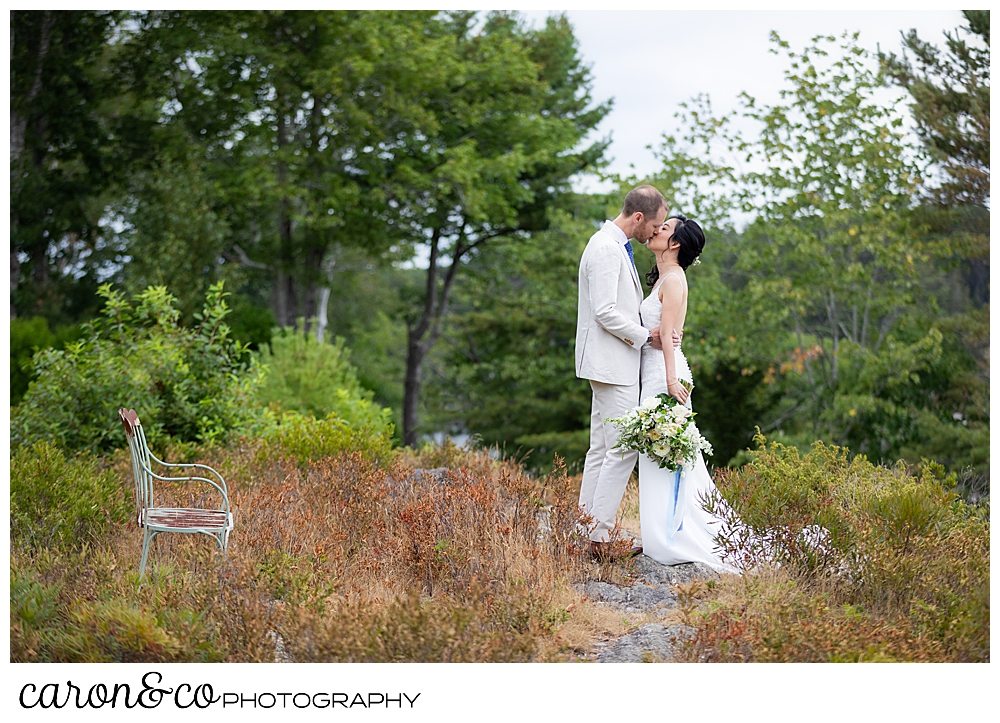 bride and groom kissing near a bench at Grey Havens Inn wedding, Georgetown Maine