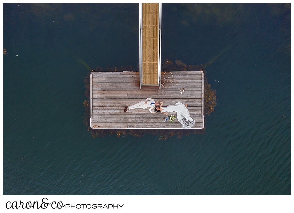 maine drone wedding photo of a bride and groom lying on a dock at a Grey Havens Inn wedding, Georgetown Maine