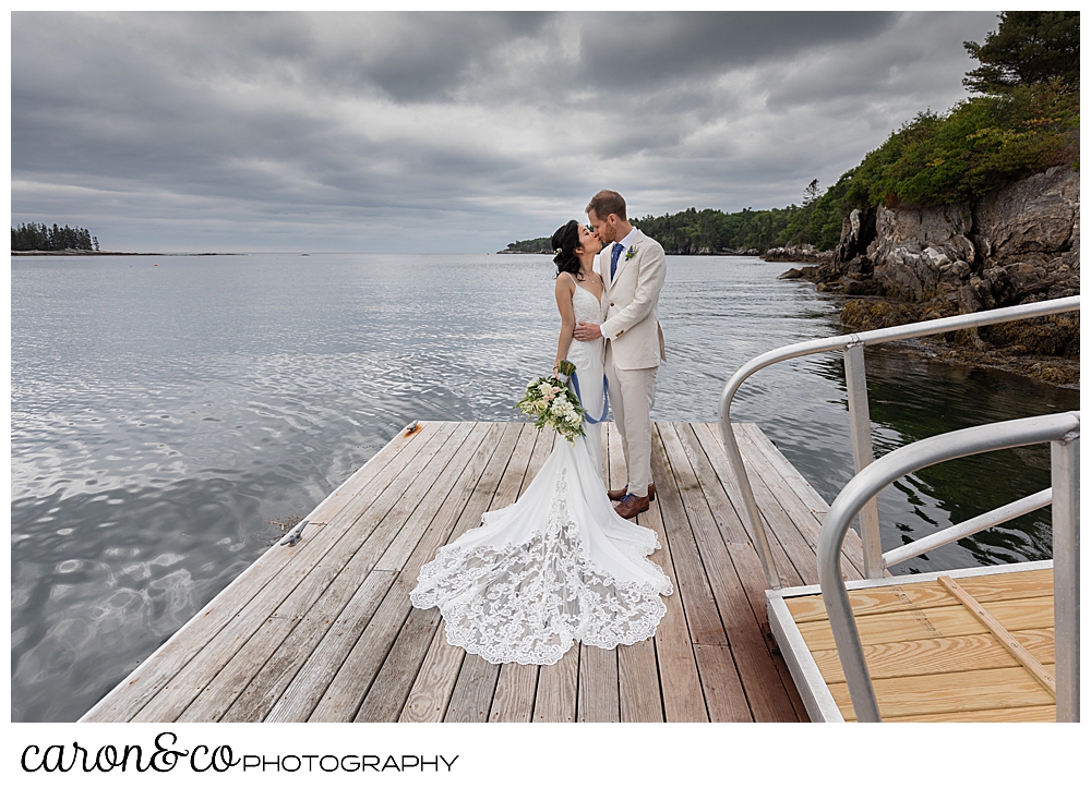 bride and groom kissing on a dock with a cloudy sky, at a Grey Havens Inn wedding, Georgetown Maine