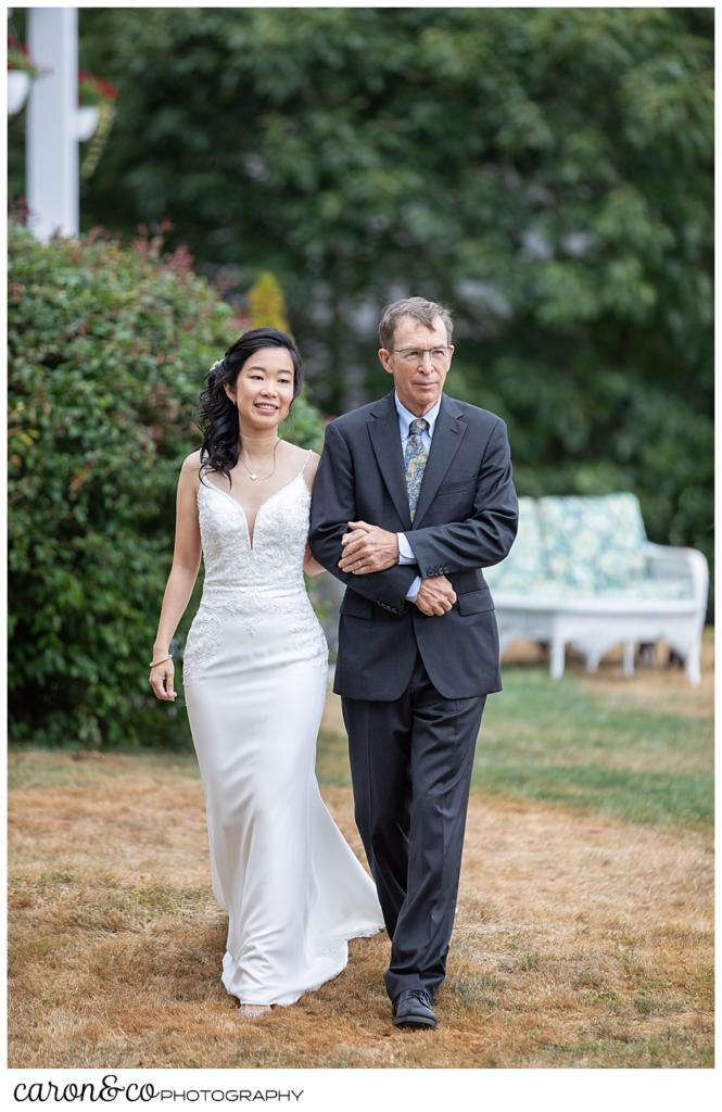 bride and her father-in-law-to-be, walk towards a Grey havens Inn wedding ceremony, Georgetown Maine